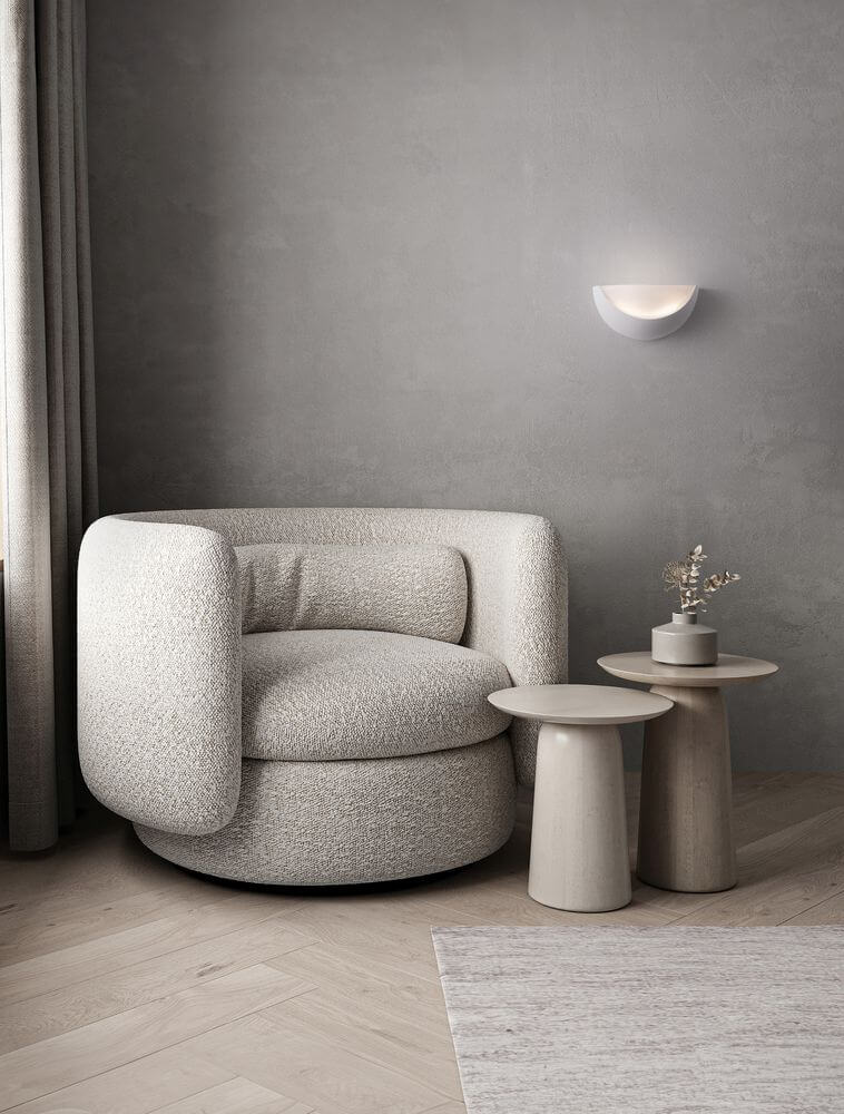 Alas Wandleuchte E14 über einem modernen, runden, hellen Sessel und minimalistischen Beistelltischen in einem grauen Raum.