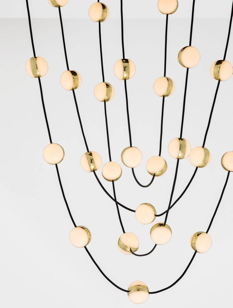 Detailansicht der Alcinoe LED Pendelleuchte Ø 84cm mit goldenen Elementen und schwarzen Kabeln.