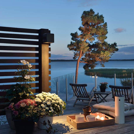 Amalfi LED outdoor wall light incl. transformer 12V black on a terrace at sunset with flowers and candles.