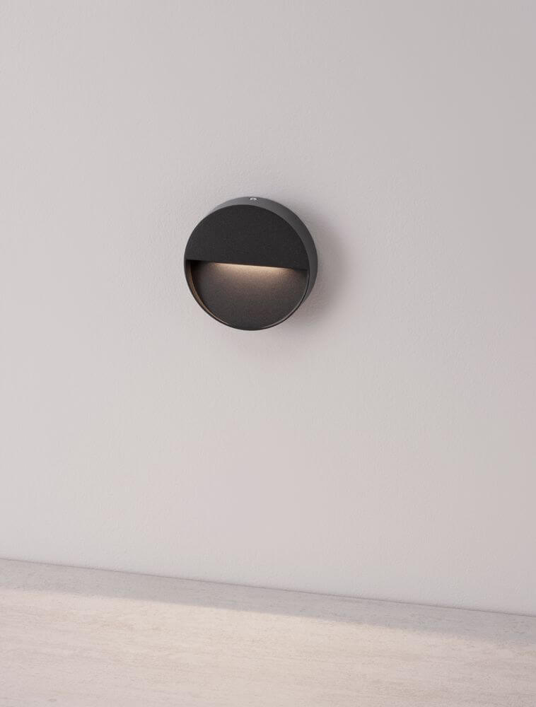 Arne LED Außenwandleuchte Ø 12cm IP54 an einer Wand montiert, mit eleganter anthrazitfarbener Oberfläche.