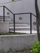 Arne LED Außenwandleuchte Ø 12cm IP54 an einer Treppe in moderner Umgebung mit Beton und Pflanzen.