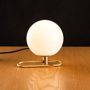 Artemide NH 1217 Tischlampe mit weißem Glas und Messingring auf Holztisch
