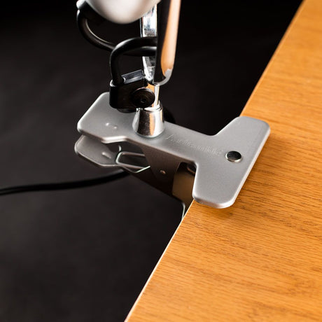 Artemide Tolomeo Pinza Klemmleuchte mit drehbarem Arm und Klemmmechanismus auf Holzoberfläche