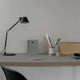 Schreibtisch mit Artemide Tolomeo Micro Tischlampe, Notizbuch, Stiften und minimalistischem Büro-Setup.