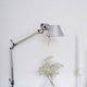 Artemide Tolomeo Micro Wandleuchte schwenkbar an einer Wand mit Dekoration und Kerze.