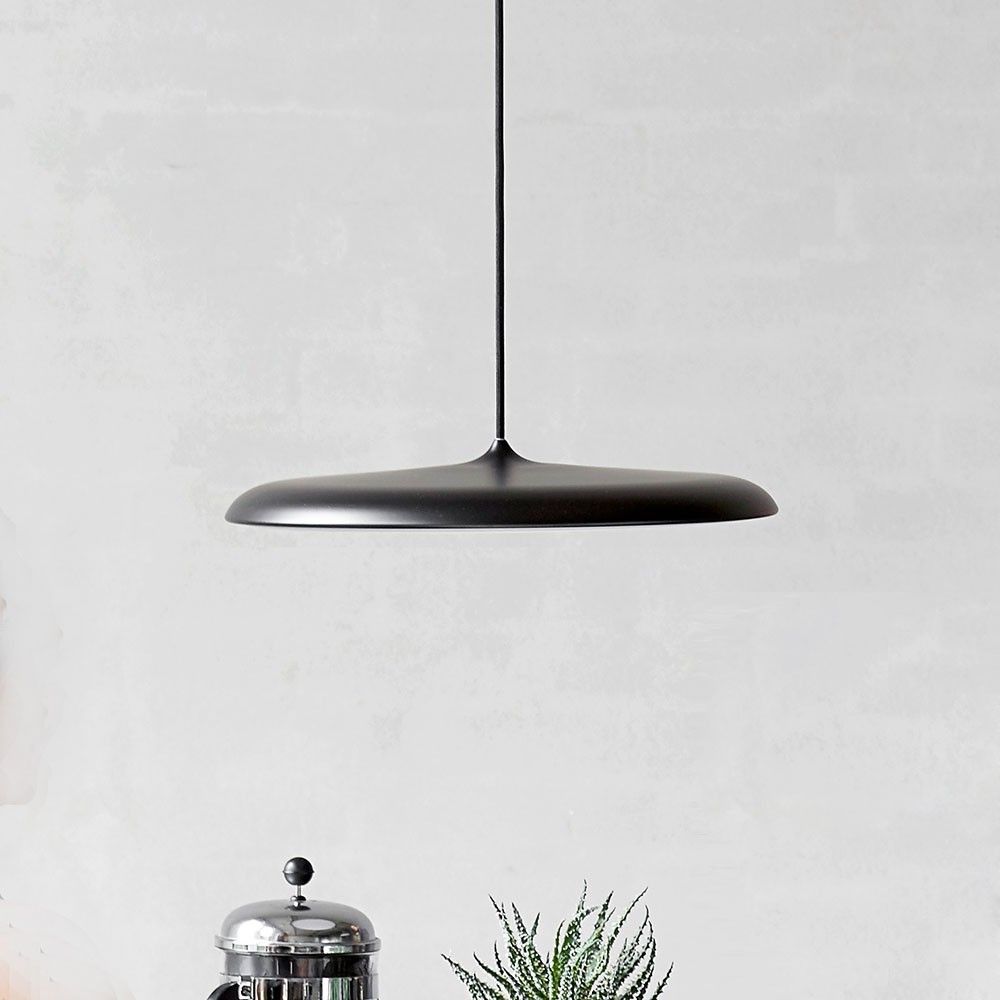 Artist 25 LED Pendelleuchte Ø 25cm Dimmbar Schwarz über einem Tisch mit Pflanzen und einem Kaffeezubereiter.