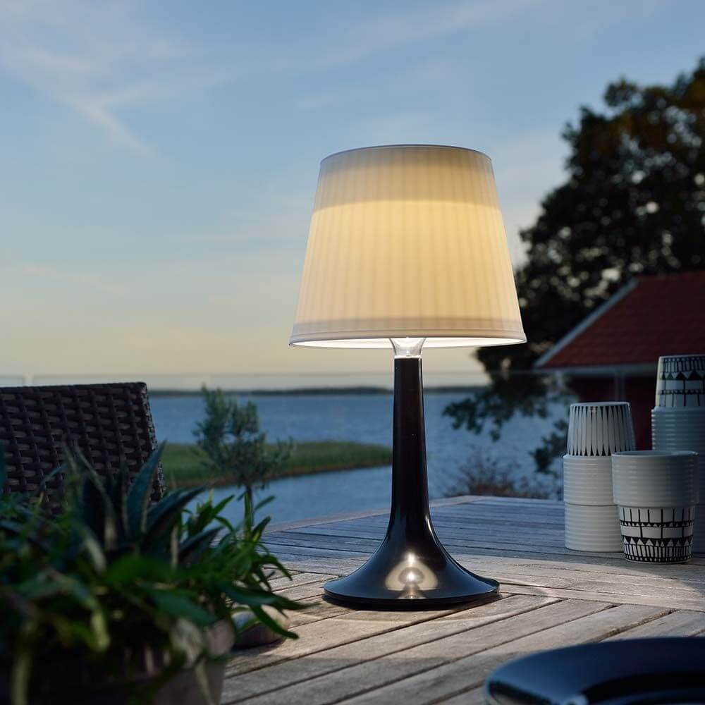 LED Tischlampe Assisi Schwarz auf einem Tisch im Freien bei Sonnenuntergang.