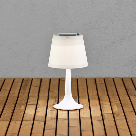 Solar LED table lamp Assisi White on a wooden terrace, with a modern design and solar technology for outdoor use.