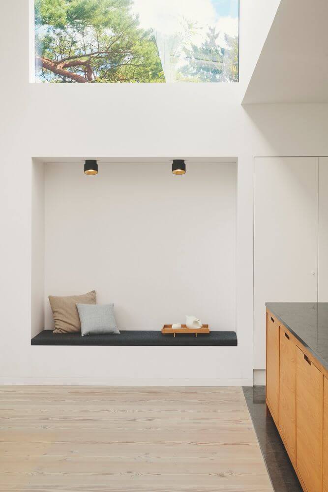 Aufbaustrahler Torone über Leseecke in modernem Wohnraum, schwarze Deckenaufbaustrahler akzentuieren Fensterbank