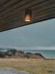 Außendeckenlampe Aludra Seaside IP54 an einer Holzdecke mit Blick auf das Meer.