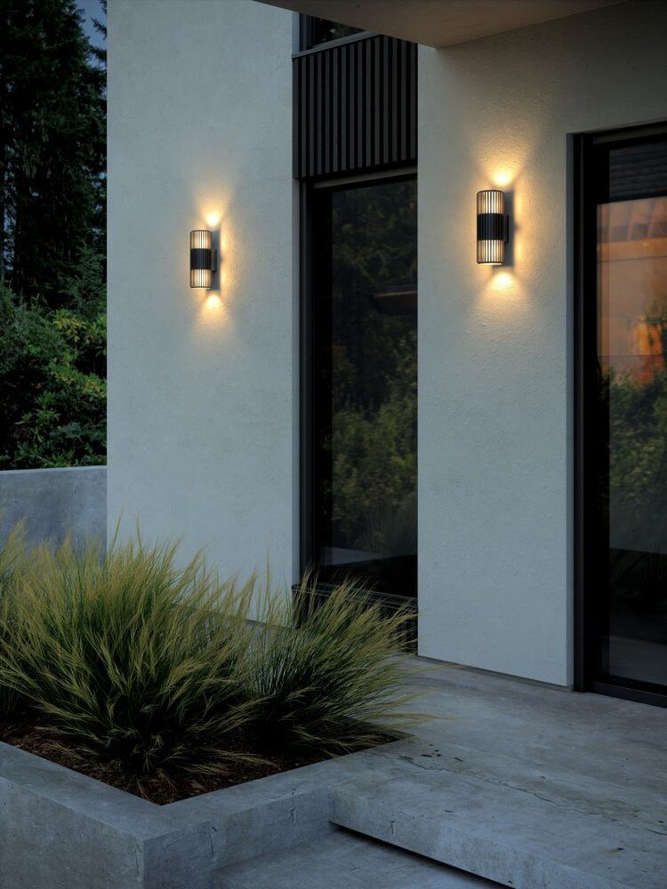 Außenwandlampe Aludra Double Seaside IP54 an einer modernen Hauswand, erzeugt warmes Licht.