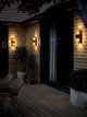 Außenwandlampe Aludra Double Seaside IP54 an einer Hauswand, strahlend Licht in dunklem Ambiente.