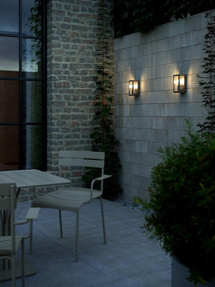 Außenwandlampe Luchy IP44 an einer Mauer im Außenbereich mit modernen Möbeln.