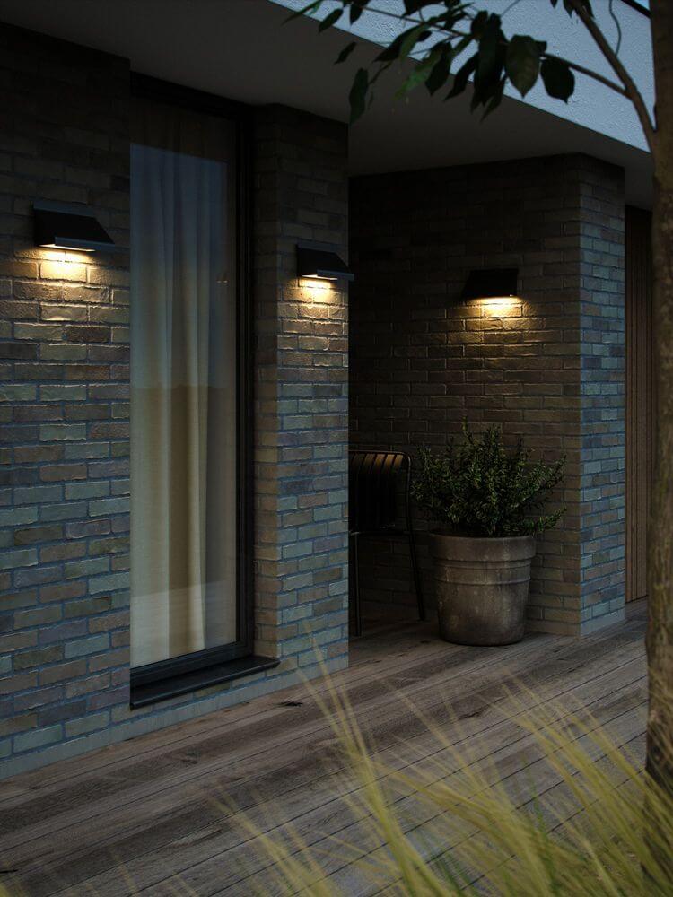 Außenwandlampe Tadas IP54 an modernen Backsteinwänden mit angenehmem Licht und minimalistischem Design.