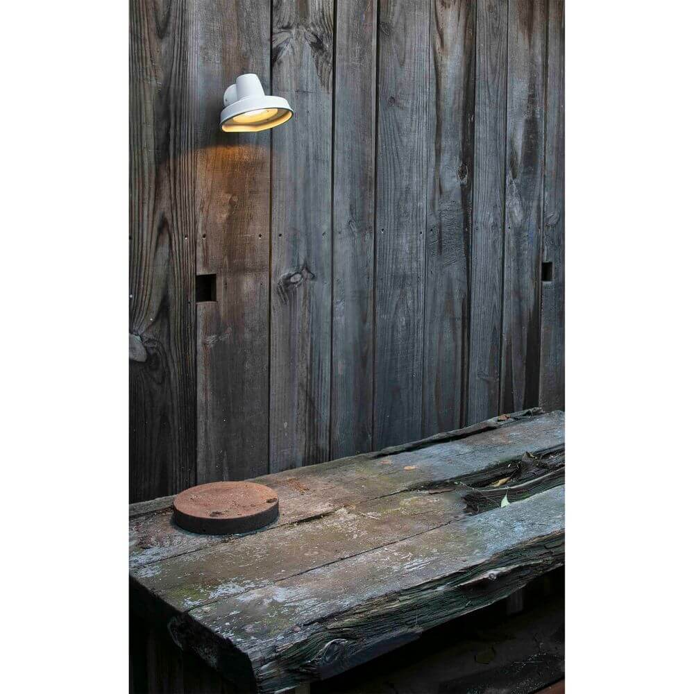 Außenwandleuchte BRONX IP44 Weiß an einer Holzwand über einem Tisch.