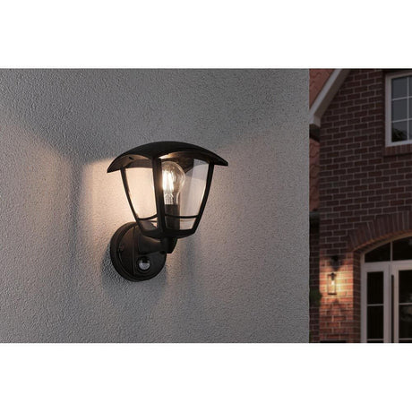 Classic Curved outdoor wall light with sensor, black installed on a wall, offers nostalgic lighting.
