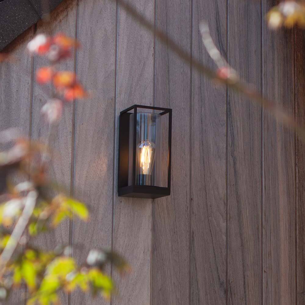 Außenwandleuchte Flair an einer Holzfassade, elegant beleuchtet mit warmem Licht.