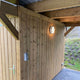 Außenwandleuchte Seine IP54 Anthrazit an einer Holzwand, Licht strahlt gleichmäßig aus dem runden, flachen Gehäuse.