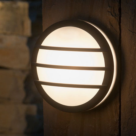 Außenwandleuchte Seine IP54 Anthrazit an einer Wand montiert, runde, flache Form mit diffundierendem Licht.