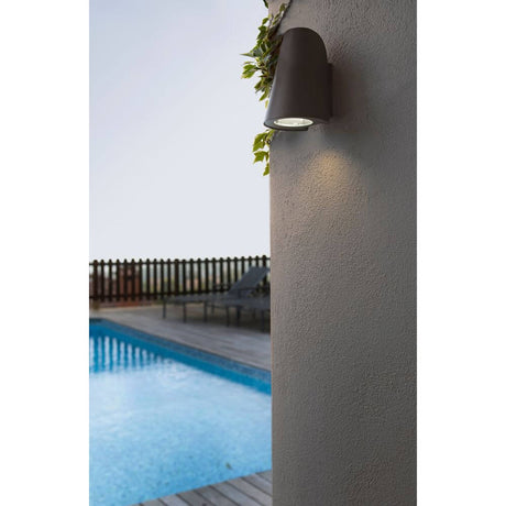 Außenwandleuchte TINIA IP44 Dunkelgrau an einer Wand neben einem Pool bei Dämmerung