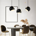 Moderne s.luce Ball Pendelleuchten in Schwarz über stilvollem Esstisch im eleganten Interieur.