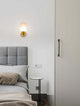Elegante Balor Wandleuchte Gold neben einem Bett in modernem Schlafzimmer-Design.