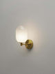 Balor Wandleuchte Gold an einer Wand montiert mit opalglas Leuchtmittel und modernem Design.