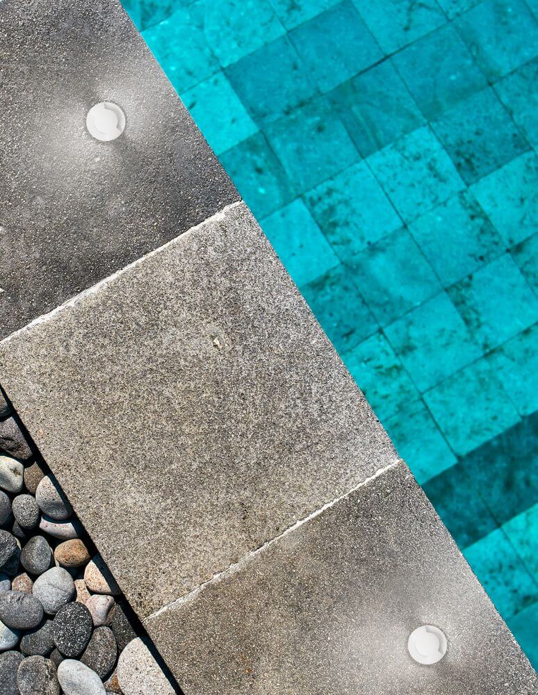 Bang LED Außenbodeneinbauleuchte Nickel IP67 in stilvoller Umgebung am Pool mit dekorativem Kies.