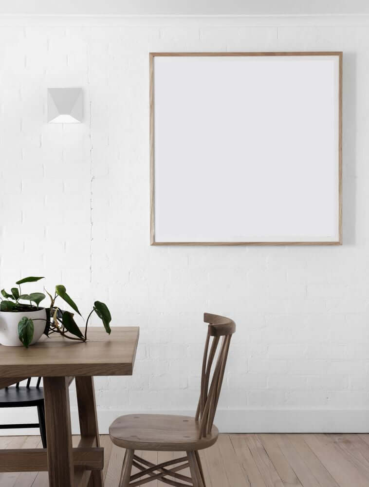 Moderne Bazz LED Wandleuchte 3000K an einer weißen Wand neben einem Holztisch.