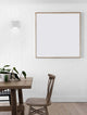 Moderne Bazz LED Wandleuchte 3000K an einer weißen Wand neben einem Holztisch.