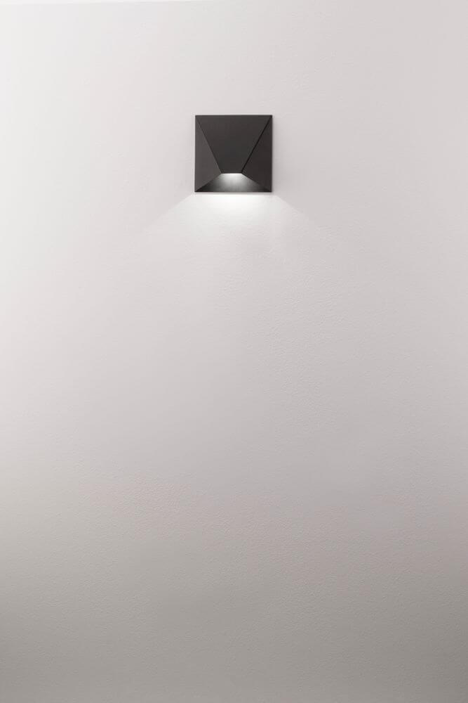 Bazz LED Wandleuchte 3000K an weißer Wand, modernes Design aus schwarzem Aluminium.