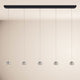 s.luce Beam LED Esstisch-Pendelleuchte Balken 120cm mit fünf eleganten Leuchtkugeln an einem schwarzen Balken.