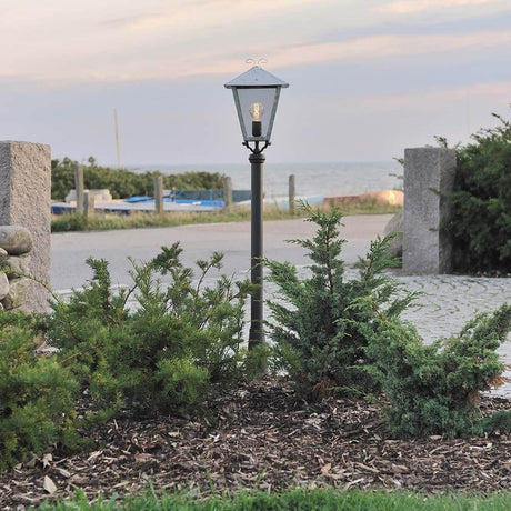Benu lampada da percorso in acciaio zincato, vetro acrilico fumé in un paesaggio giardino.