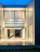 Moderner Wohnraum mit verglasten Wänden, Treppe und eleganter Innenarchitektur bei Nacht.