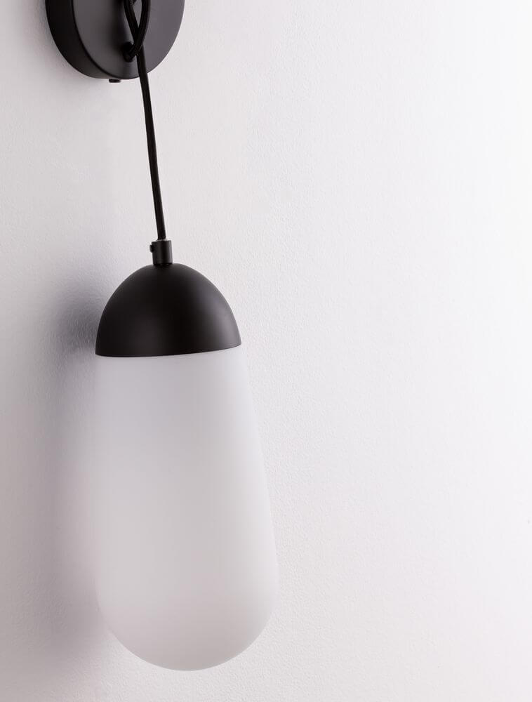 Blaky Wandleuchte Schwarz, Weiß mit mattem Opalglas und modernem Design an einer Wand installiert.