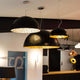 Schwarze Pendelleuchten in Haubenform mit goldener Innenfläche, ideal für moderne Räume und Essbereiche.