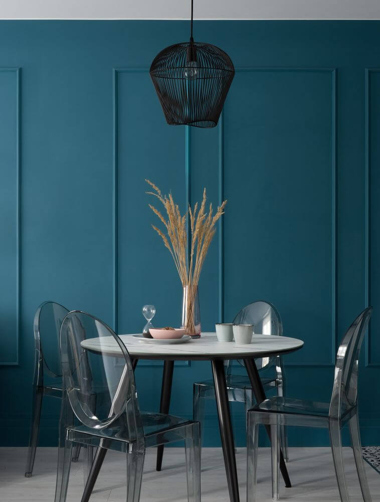 Bredo Pendelleuchte Ø 31,5cm Schwarz über einem stilvollen Esstisch mit modernen Stühlen und blauer Wand.
