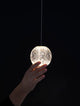 Brillante LED Pendelleuchte Ø 12cm 3200K in einer eleganten Hand gehalten, strahlt modernes Design und Eleganz aus.