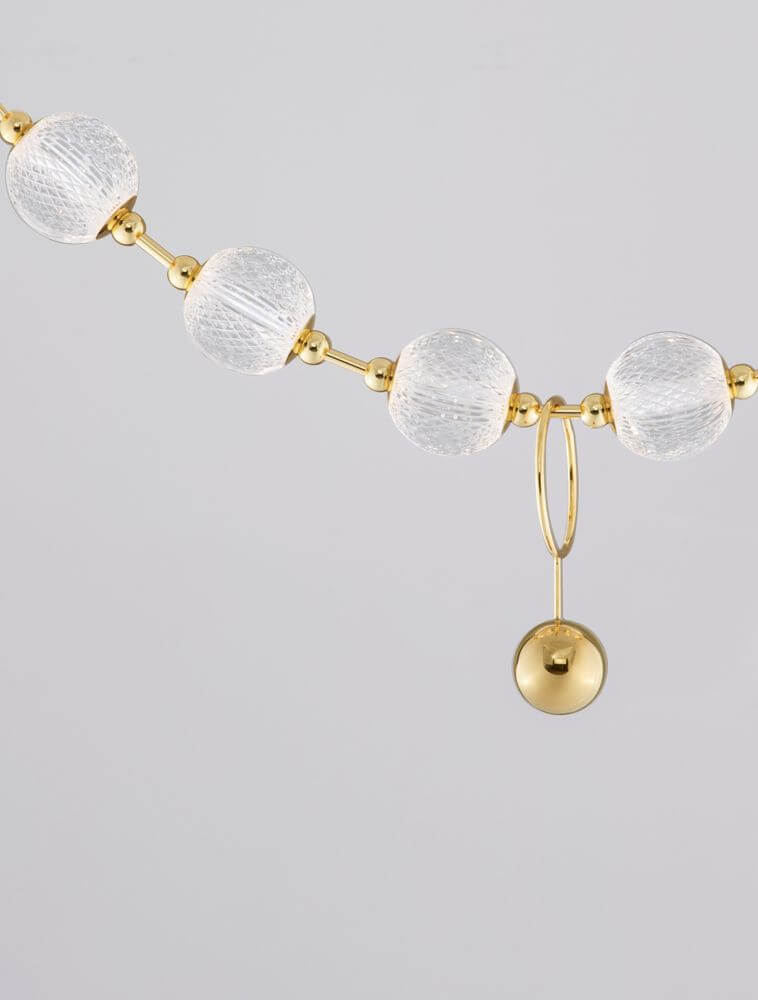 Dekorative goldene und gläserne Perlenkette mit elegantem Anhänger für stilvolle Wohnaccessoires.