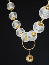 Brillante Pendelleuchte mit glasklaren Kristallkugeln und goldenen Akzenten für elegantes Wohnambiente.