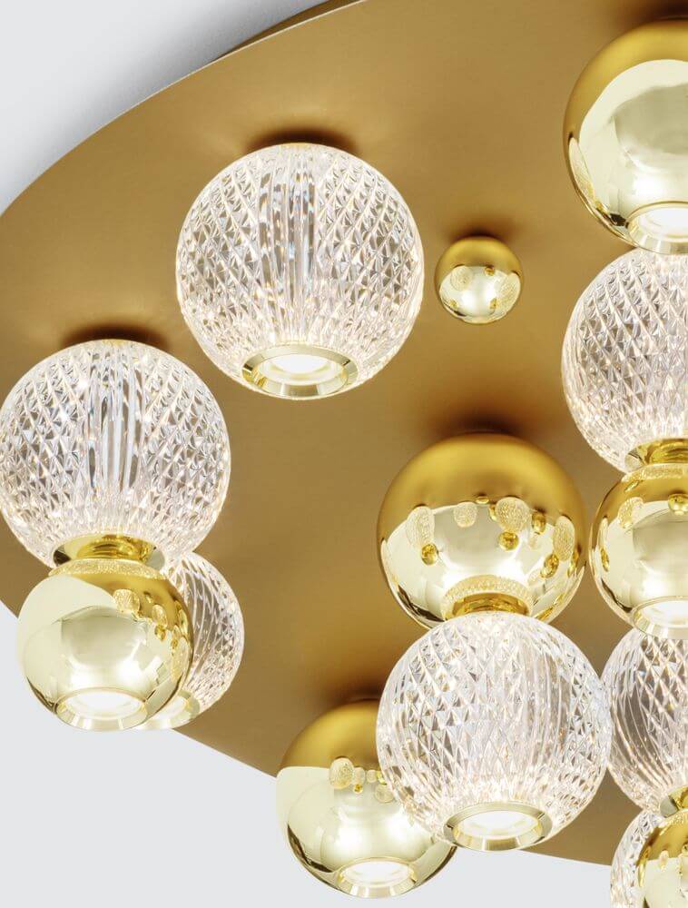 Detailansicht der Brille LED Deckenleuchte mit goldenen und gläsernen Kugeln, die warmweißes Licht spendet.