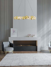 Brille LED 12-light pendant light Ø 94 cm 3200K gold above a modern living room with fireplace