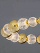Brille LED Pendelleuchte 12-flammig Ø 94cm 3200K Gold mit glänzenden goldenen und lichtdurchlässigen Glaskugeln.