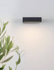 Brin LED Außenwandleuchte 3000K Anthrazit IP65 an einer Wand montiert, strahlt warmes Licht aus.