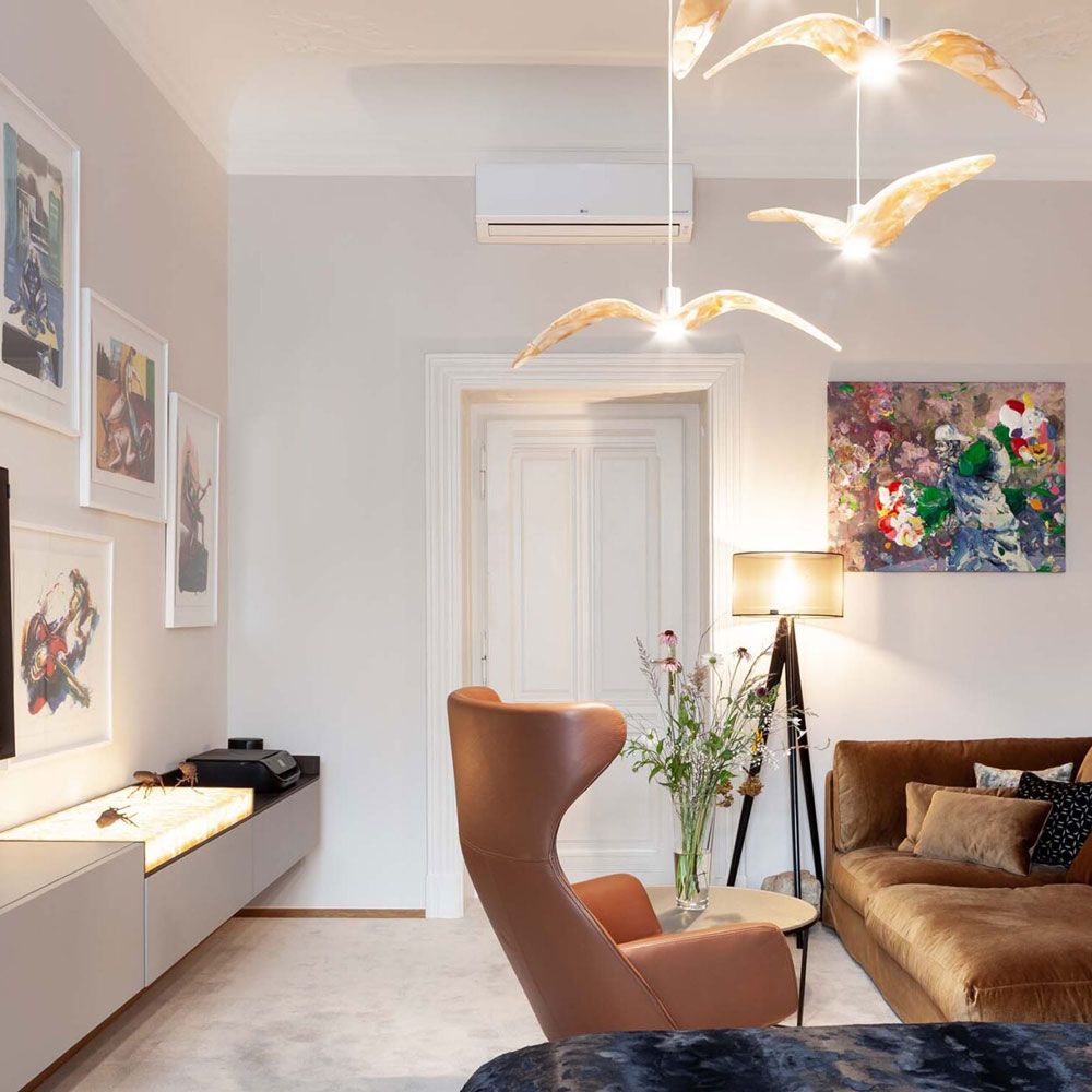 Brokis Hängeleuchte Night Birds mit normalem Flügel in modernem Wohnraum mit beiger Couch und Kunstwerken.