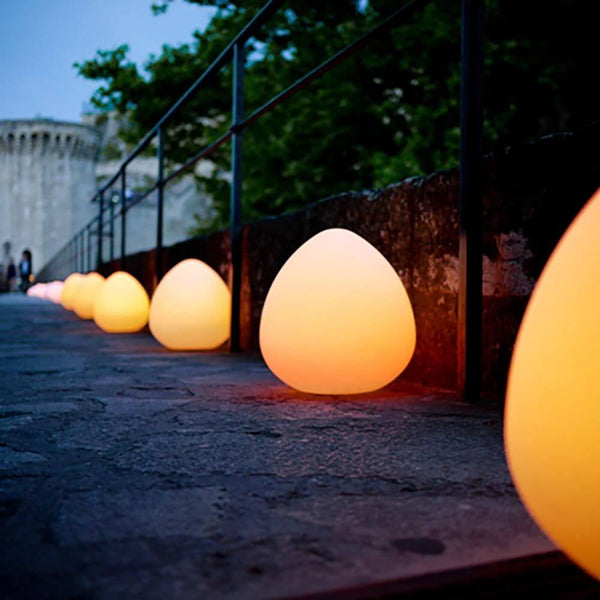 Shatterproof LED rechargeable lamp Stone with app control in warm light on a garden promenade