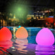 Bunte LED-Akkuleuchten Stone im Wasser bei Nacht, schaffen eine entspannte Atmosphäre im Garten oder Poolbereich.