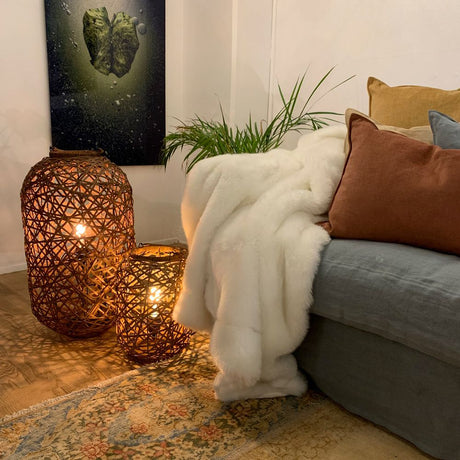 Diego floor lamp made of rattan next to a cozy sofa with a blanket and cushions, stylish lighting in the room.
