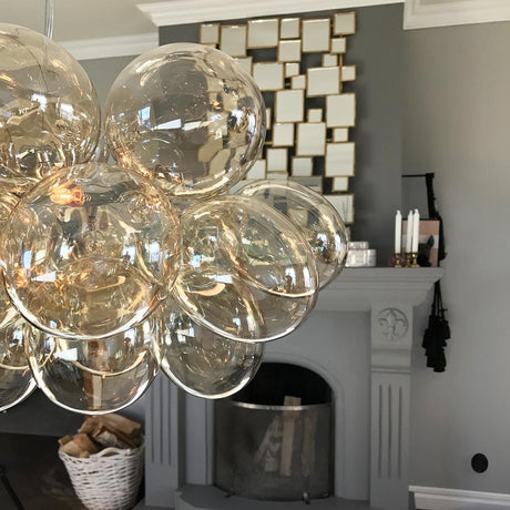 Lampada a sospensione in vetro Gross Bar 80 cm con delicate sfere di vetro sopra un elegante soggiorno.