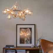 Candeeiro suspenso de vidro Splendor 15 luzes Âmbar num espaço habitacional elegante com uma obra de arte decorativa na parede.